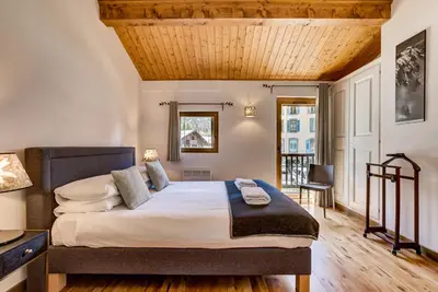 a bedroom with a large bed with a wooden ceiling at Pic Janvier - Alpes Travel - Les Praz (sleeps 4-6) in Chamonix-Mont-Blanc