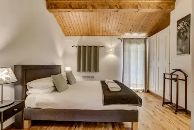 a bedroom with a large bed with a wooden ceiling at Pic Janvier - Alpes Travel - Les Praz (sleeps 4-6) in Chamonix-Mont-Blanc