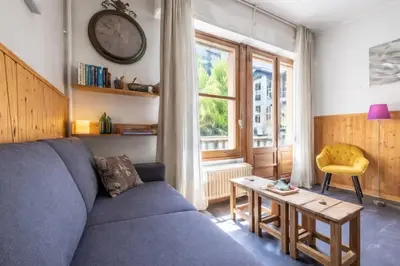 a living room with a couch and a table and a clock at Warm Haven in Chamonix With balcony in Chamonix-Mont-Blanc