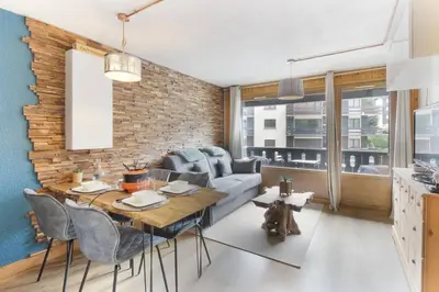 a living room with a dining table and a brick wall at Les Dryades - Rénové - Balcon avec vue Mt Blanc in Les Houches