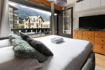 a bedroom with a large bed with a large window at Les Dryades - Rénové - Balcon avec vue Mt Blanc in Les Houches