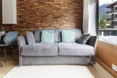 a couch in a living room with a brick wall at Les Dryades - Rénové - Balcon avec vue Mt Blanc in Les Houches