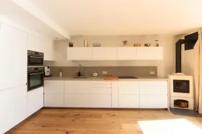 a kitchen with white cabinets and a wooden floor at Les Gaillands in Chamonix-Mont-Blanc
