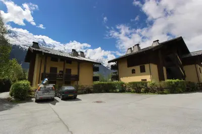 a building with two cars parked in a parking lot at Les Gaillands in Chamonix-Mont-Blanc