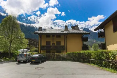 a house with cars parked in a parking lot at Les Capucins - Calm - Mont-Blanc - Lake Gaillland in Chamonix-Mont-Blanc