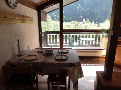 a table in a room with a view of a balcony at Résidence Mont'seu - Mont'seu C401 MAE-6354 in Les Contamines-Montjoie
