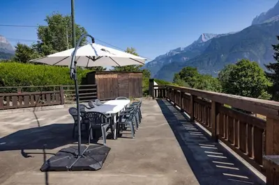 a table and chairs with an umbrella on a balcony at Appartement l'éterlou in Sallanches