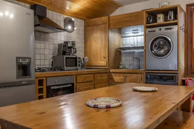a kitchen with a wooden table and a washer and dryer at Appartement l'éterlou in Sallanches