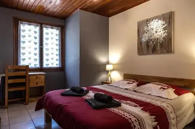 a bedroom with a large bed with a red blanket at Appartement l'éterlou in Sallanches