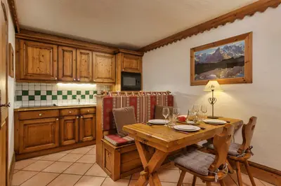 a kitchen with a wooden table and a table and chairs at Grepon -City Center - Free Swimming pool, Sauna, Gym - Free Parking - By Cozee Rentals in Chamonix-Mont-Blanc