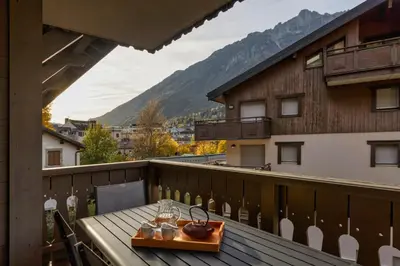 a table on a balcony with a view of a mountain at Grepon -City Center - Free Swimming pool, Sauna, Gym - Free Parking - By Cozee Rentals in Chamonix-Mont-Blanc