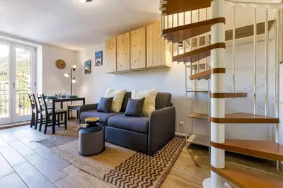 a living room with a couch and a dining room at Epicea - Chic 2BR in city center, next to Train Station - By Cozee Rentals in Chamonix-Mont-Blanc