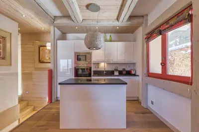 a kitchen with white cabinets and a large island at La Blaitière - Luxe Apart Center Chamonix , Next to Piste Planard - By Cozee Rentals in Chamonix-Mont-Blanc