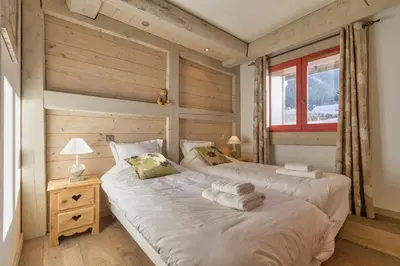 two twin beds in a room with wooden walls at La Blaitière - Luxe Apart Center Chamonix , Next to Piste Planard - By Cozee Rentals in Chamonix-Mont-Blanc