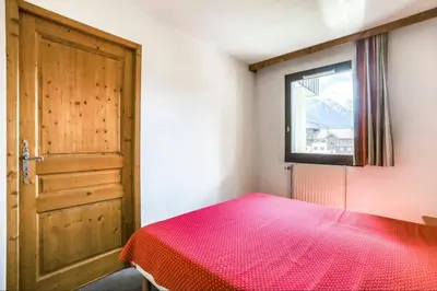 a bedroom with a red bed and a window at Nice Apt With Balcon In The Downtown ! in Chamonix-Mont-Blanc