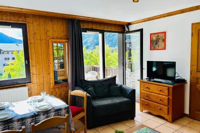 a living room with a table and a chair at Nice Apt With Balcon In The Downtown ! in Chamonix-Mont-Blanc