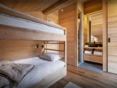 a bedroom with two bunk beds in a wooden cabin at Chalet Fanfoua - OVO Network in Combloux