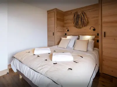 a bedroom with a large white bed with wooden walls at Chalet Fanfoua - OVO Network in Combloux