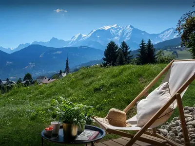 a chair with a hat on a table with a view of mountains at Chalet Fanfoua - OVO Network in Combloux
