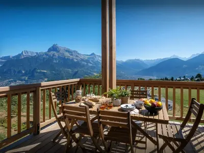 a table on a deck with a view of mountains at Chalet Fanfoua - OVO Network in Combloux