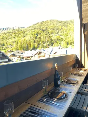 a table with wine glasses and a view of a mountain at Duplex Samoëns 4/6 couchages in Samoëns