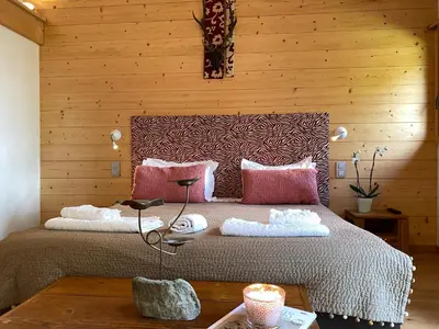 a bedroom with a large bed with a wooden wall at Chalet Isabelle Mountain lodge 5 star 5 bedroom en suite sauna jacuzzi in Chamonix-Mont-Blanc