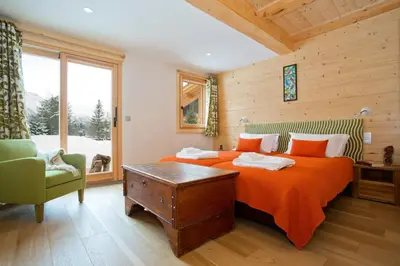 a bedroom with a bed with orange sheets and a chair at Chalet Isabelle Mountain lodge 5 star 5 bedroom en suite sauna jacuzzi in Chamonix-Mont-Blanc