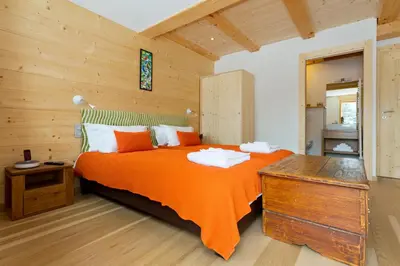 a bedroom with a large bed with an orange blanket at Chalet Isabelle Mountain lodge 5 star 5 bedroom en suite sauna jacuzzi in Chamonix-Mont-Blanc