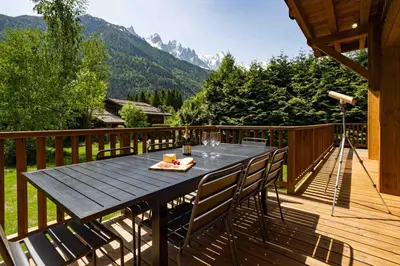 a wooden deck with a table and chairs on it at Chalet du Gouter - Chamonix All Year in Chamonix-Mont-Blanc