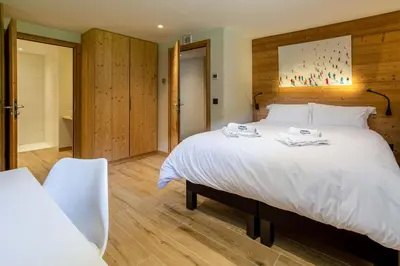 a bedroom with a large white bed and a bathroom at Chalet du Gouter - Chamonix All Year in Chamonix-Mont-Blanc