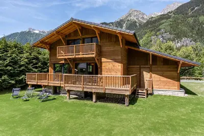 a log cabin with a deck and two chairs at Chalet du Gouter - Chamonix All Year in Chamonix-Mont-Blanc