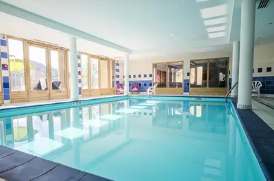 a swimming pool with blue water in a building at Studio & piscine intérieure, vue Mont D'Arbois in Saint-Gervais-les-Bains
