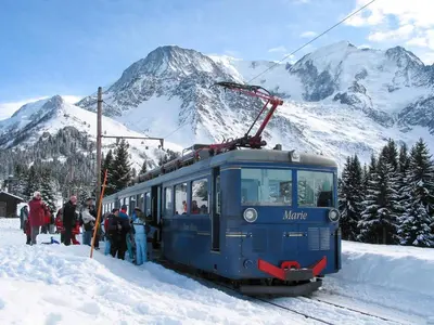 a group of people standing next to a train in the snow at Studio & piscine intérieure, vue Mont D'Arbois in Saint-Gervais-les-Bains