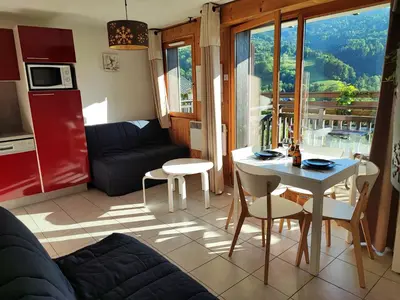 a living room with a couch and a table and a kitchen at Studio & piscine intérieure, vue Mont D'Arbois in Saint-Gervais-les-Bains