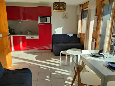 a kitchen and a living room with red cabinets at Studio & piscine intérieure, vue Mont D'Arbois in Saint-Gervais-les-Bains