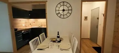 a kitchen with a table with a clock on the wall at Le Flory'lège in Saint-Gervais-les-Bains