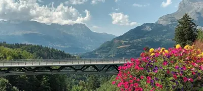a bridge with flowers and mountains in the background at Le Flory'lège in Saint-Gervais-les-Bains