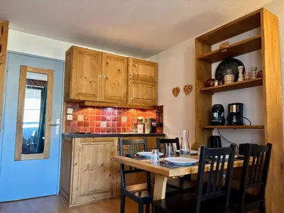 a kitchen with wooden cabinets and a table with chairs at Studio rénové au centre avec balcon et parking - FR-1-624-106 in Samoëns