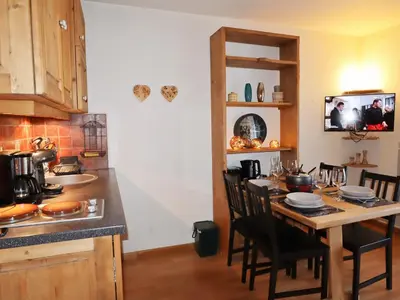 a kitchen with a table with chairs and a counter top at Studio rénové au centre avec balcon et parking - FR-1-624-106 in Samoëns