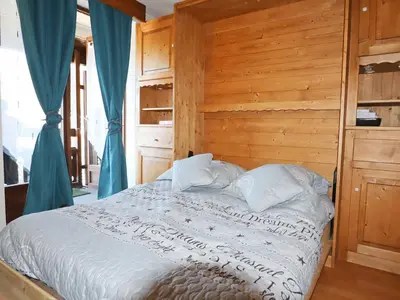 a bedroom with a bed with a wooden wall at Studio rénové au centre avec balcon et parking - FR-1-624-106 in Samoëns