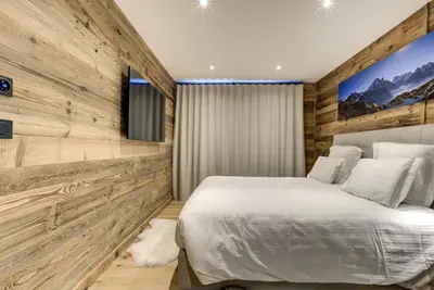 a bedroom with a white bed and wooden walls at Chalet Lily by Brennus Chamonix in Chamonix-Mont-Blanc