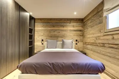 a bed in a room with a wooden wall at Chalet Lily by Brennus Chamonix in Chamonix-Mont-Blanc