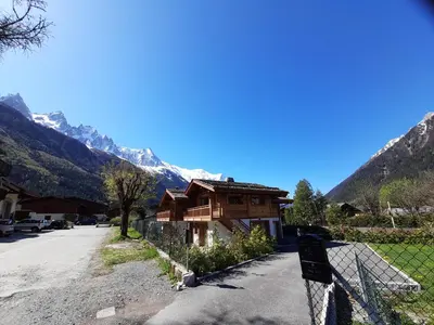 a house with a fence in front of a mountain at Chalet Lily by Brennus Chamonix in Chamonix-Mont-Blanc