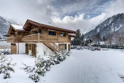 a log cabin in the snow with mountains at Chalet Lily by Brennus Chamonix in Chamonix-Mont-Blanc