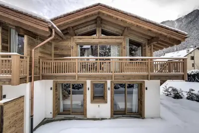 a log home with a deck in the snow at Chalet Lily by Brennus Chamonix in Chamonix-Mont-Blanc