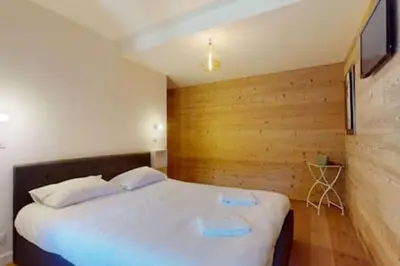 a bedroom with a white bed with a wooden wall at Les Carlines 09 in Samoëns