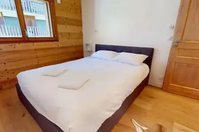 a bedroom with a bed with white sheets and a window at Les Carlines 09 in Samoëns