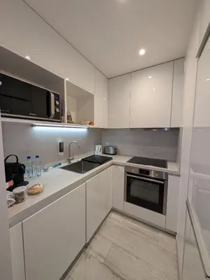a kitchen with white cabinets and a sink and a microwave at LE YAMA in Chamonix-Mont-Blanc