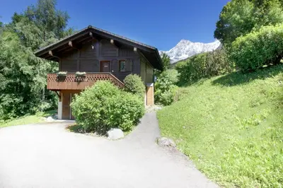 a small wooden house with a balcony on a hill at Chalet Kandahar - Piscine intérieure - Parc & Lac des Chavants - Escalade - Sentiers de Randonnée in Les Houches