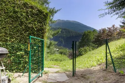 a green fence with a mountain in the background at Chalet Kandahar - Piscine intérieure - Parc & Lac des Chavants - Escalade - Sentiers de Randonnée in Les Houches